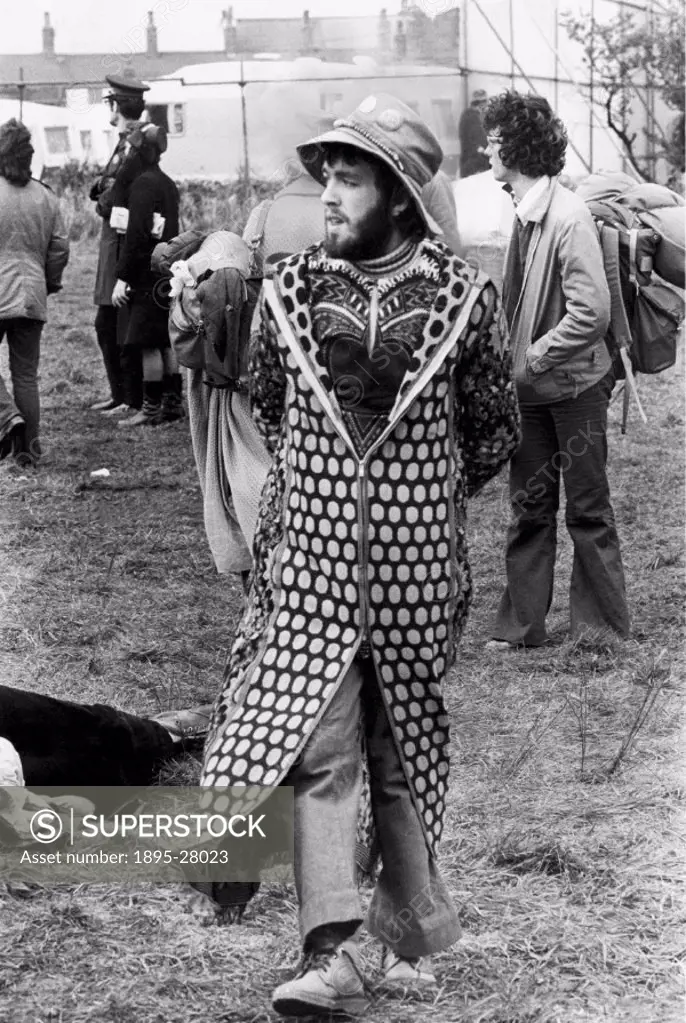 Man walking through a field in an extravagant coat at the festival held at Bickershaw, Lancashire, from Friday 5 May to Sunday 7 May 1972. The festiva...