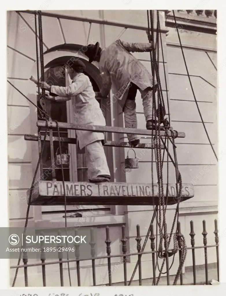 A photograph of two men painting external window frames, taken by an unknown photographer in about 1935.  The decorators stand on a suspended cradle w...