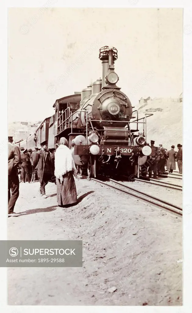 A snapshot photograph of passengers standing beside a steam train on the Russian State Railway, taken by an unknown photographer in about 1920.  This ...