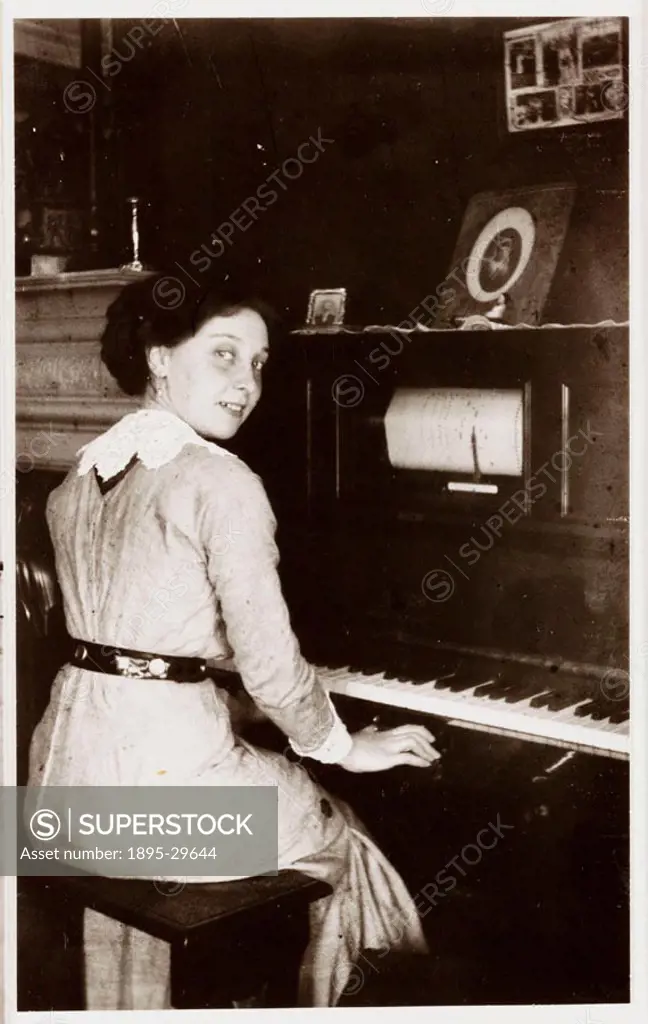A snapshot photograph of a young woman seated at a player-piano, taken by an unknown photographer in about 1910. This type of piano has a player mecha...