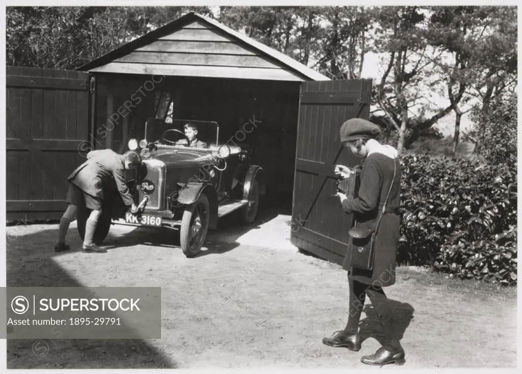 A snapshot photograph of a young girl photographing two boys and a motorcar, taken by an unknown photographer in about 1930.  Originally a shooting te...