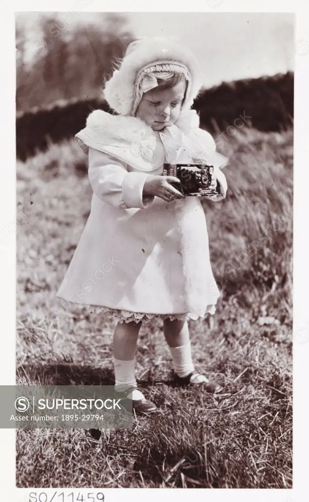 A snapshot photograph of a little girl holding a camera, taken by an unknown photographer in about 1920.  This smartly-dressed little girl is taking a...