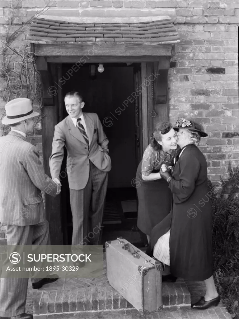 A photograph of a couple saying farewell to their guests at the door to a cottage, taken by Photographic Advertising Limited in 1950.  The photograph ...