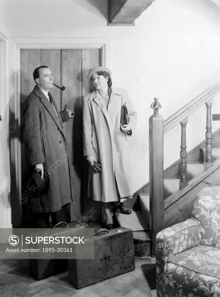 A photograph of a man and a woman standing by the door with a pair of suitcases, taken by Photographic Advertising Limited about 1950.  Photographic A...