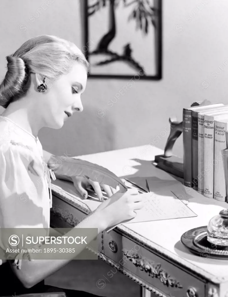 A photograph of a woman sitting at a table writing a letter, taken by Photographic Advertising Limited in 1949.  Photographic Advertising Limited was ...