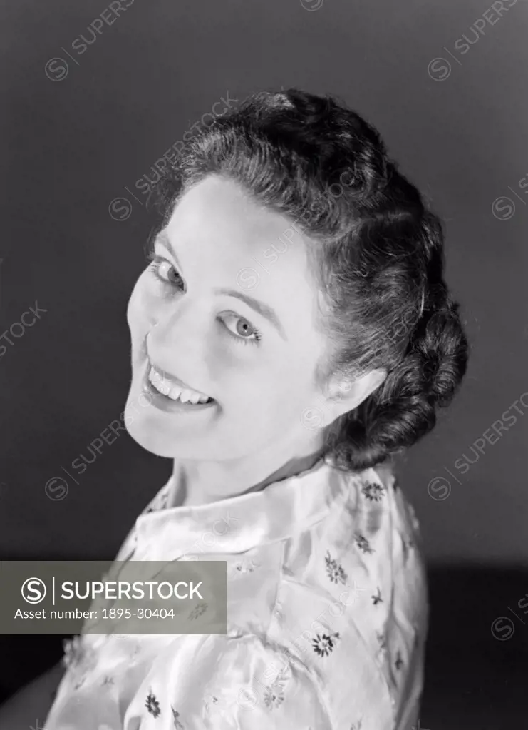 A photograph of a smiling woman looking over her shoulder, taken by Photographic Advertising Limited in 1950.  Photographic Advertising Limited was fo...