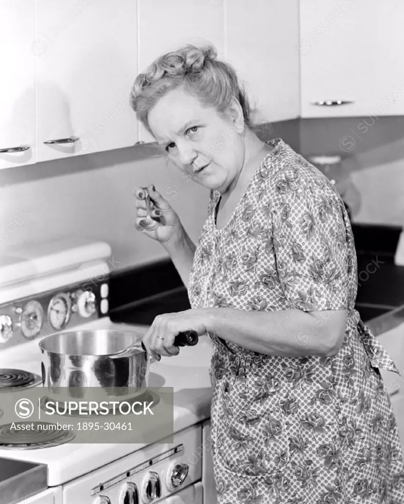 A photograph of a woman tasting food from a pan on an electric cooker, taken by Photographic Advertising Limited in 1950.  This photograph was taken i...