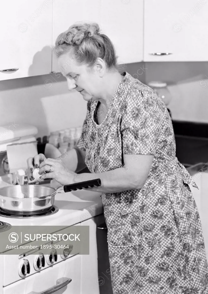 A photograph of a woman breaking an egg into a frying pan on an electric cooker, taken by Photographic Advertising Limited in 1950.  This photograph w...