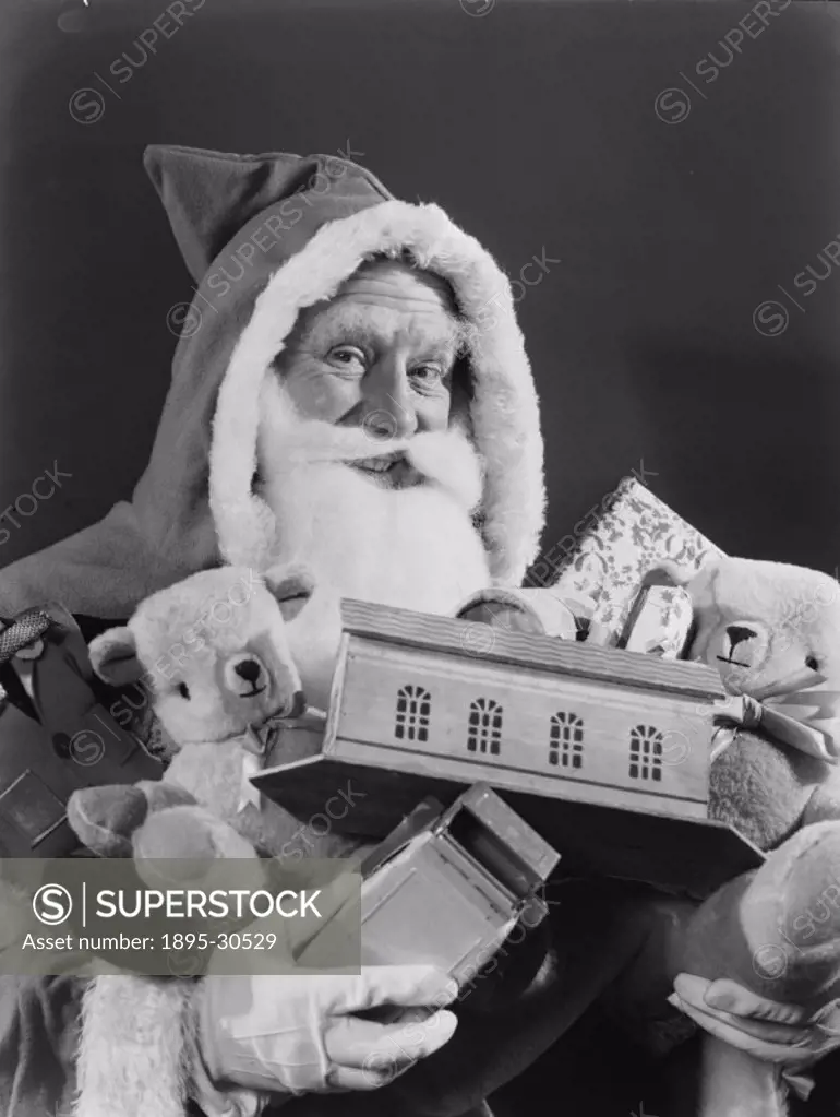 A photograph of Father Christmas carrying an armful of children´s toys, taken by Photographic Advertising Limited in 1950. Christmas is a popular subj...