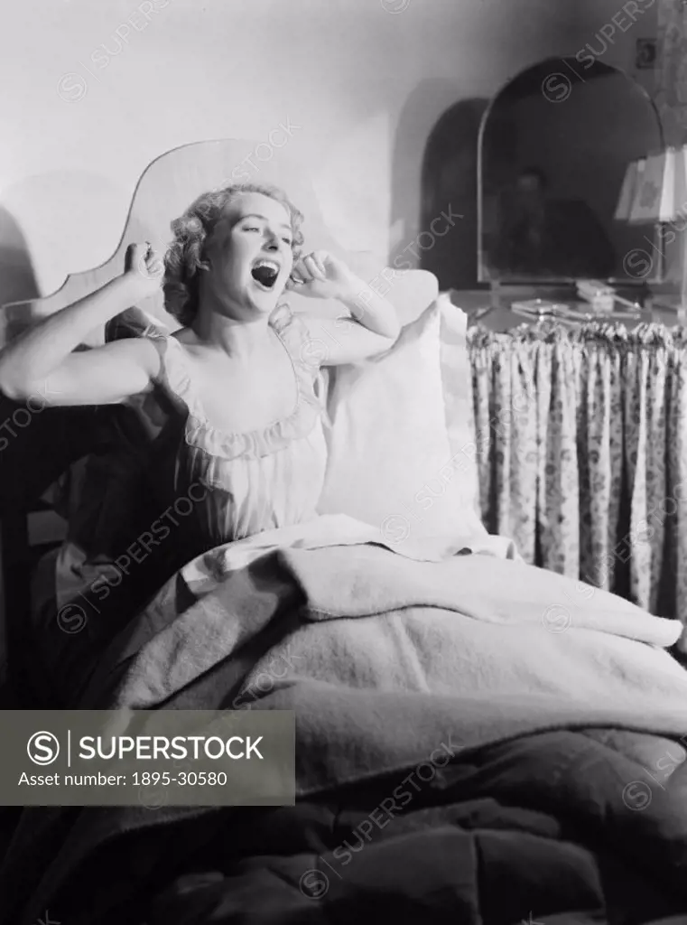 A photograph of a woman waking up in bed, stretching and yawning, taken by Photographic Advertising Limited in 1952.  This image was used in ´Woman´s ...