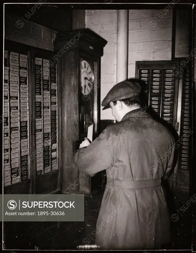 A worker ´clocking on´ a time machine used to determine the amount of time worked over any period.