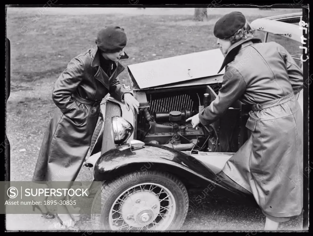 A photograph of two women examining the engine of an Armstrong-Siddeley for an advertising shoot, taken by George Woodbine for the Daily Herald newspa...