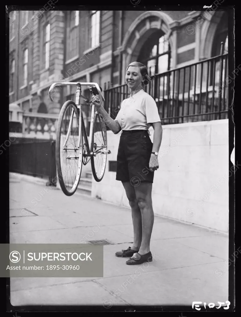 A photograph of a woman holding a lightweight bicycle, taken by Harold Tomlin for the Daily Herald newspaper on 30 October, 1934.   Said to be the lig...