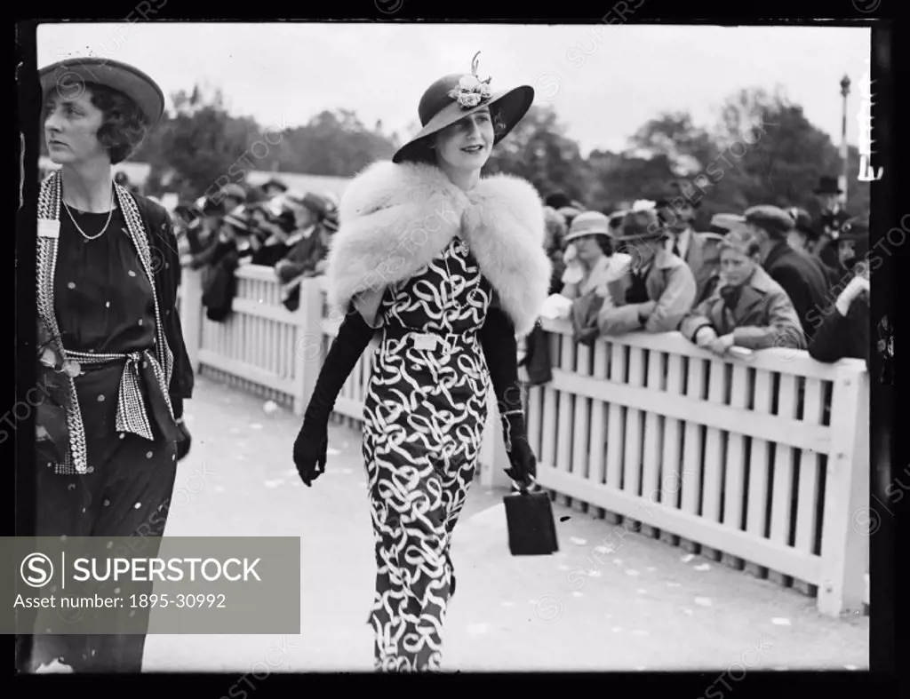 A photograph of a woman walking past the crowds on the second day of Royal Ascot for the Royal Hunt Cup, taken by Edward Malindine for the Daily Heral...