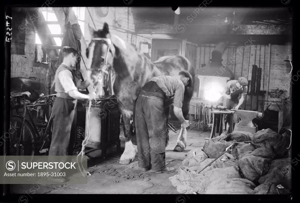A photograph of a busy blacksmith´s workshop in Camberwell, South London, taken by George Woodbine for the Daily Herald newspaper on 30 September, 193...