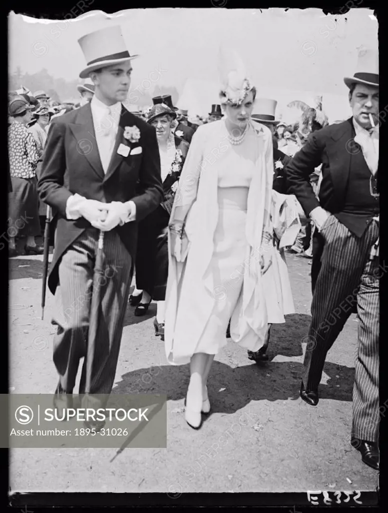 A photograph of racegoers at Royal Ascot, taken by Edward Malindine for the Daily Herald newspaper on 18 June, 1936.  The woman is fashionably dressed...