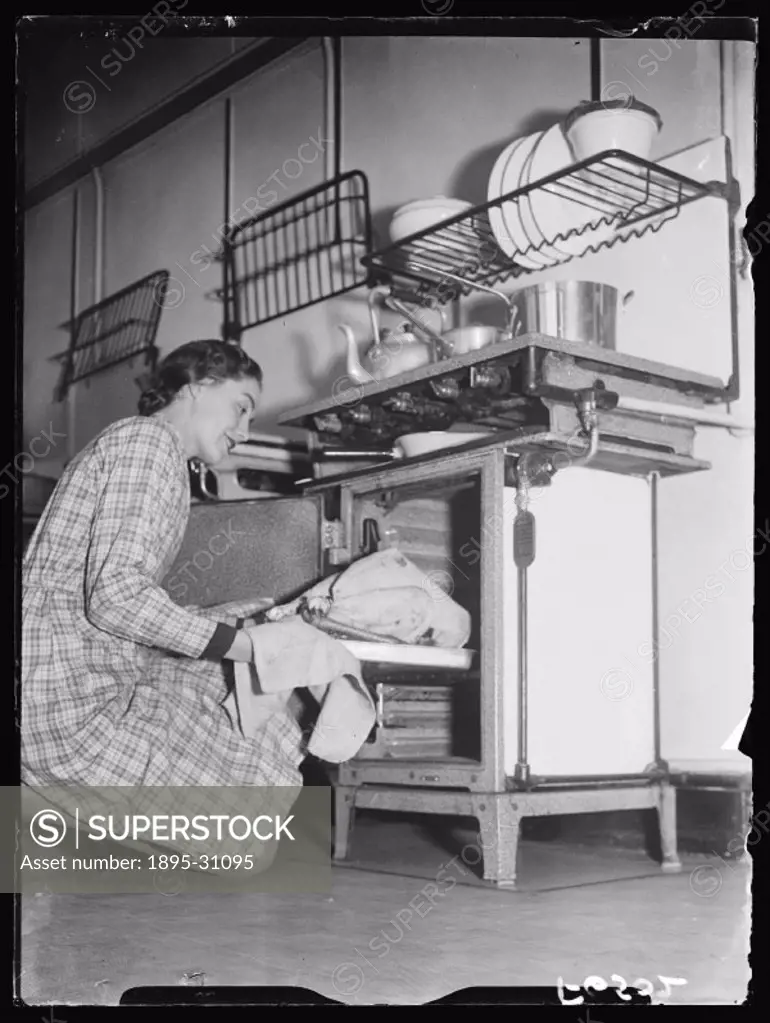 A photograph of a woman placing a turkey in a gas oven to cook, taken by Tomlin for the Daily Herald newspaper on 16 November, 1937. This photograph h...