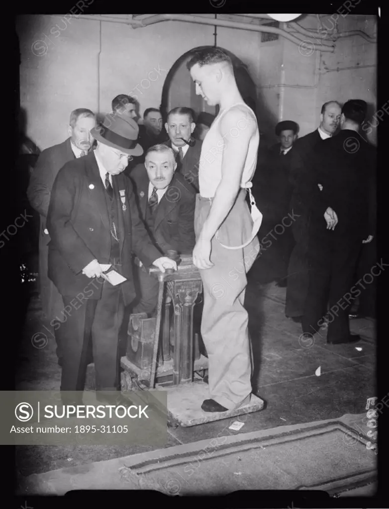 A photograph of a competitor weighing-in before the police boxing championships held at Harringay, London,  taken by Roper for the Daily Herald newspa...