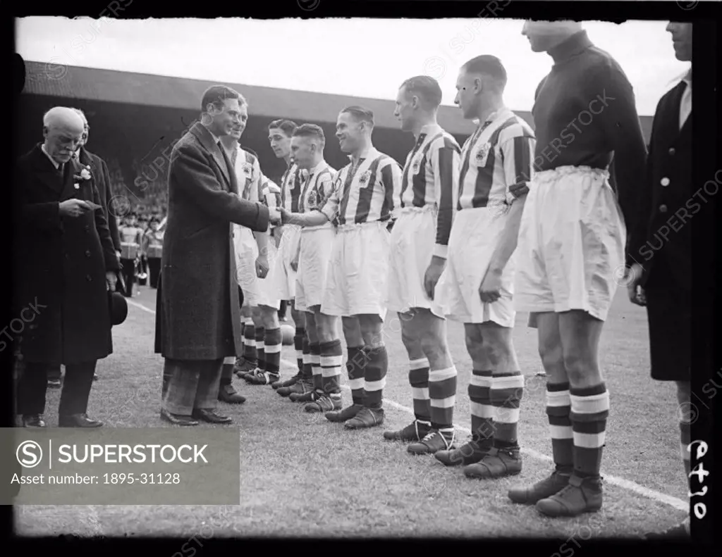 A photograph of Huddersfield Town players lining up to shake George VI´s (1895-1952) hand before the start of the 1938 FA Cup Final at Wembley Stadium...