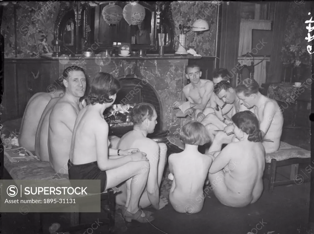 A photograph of nudists gathered at the fireside, taken by Saidman for the Daily Herald newspaper on 1 May, 1938.  These 11 members of the National Su...