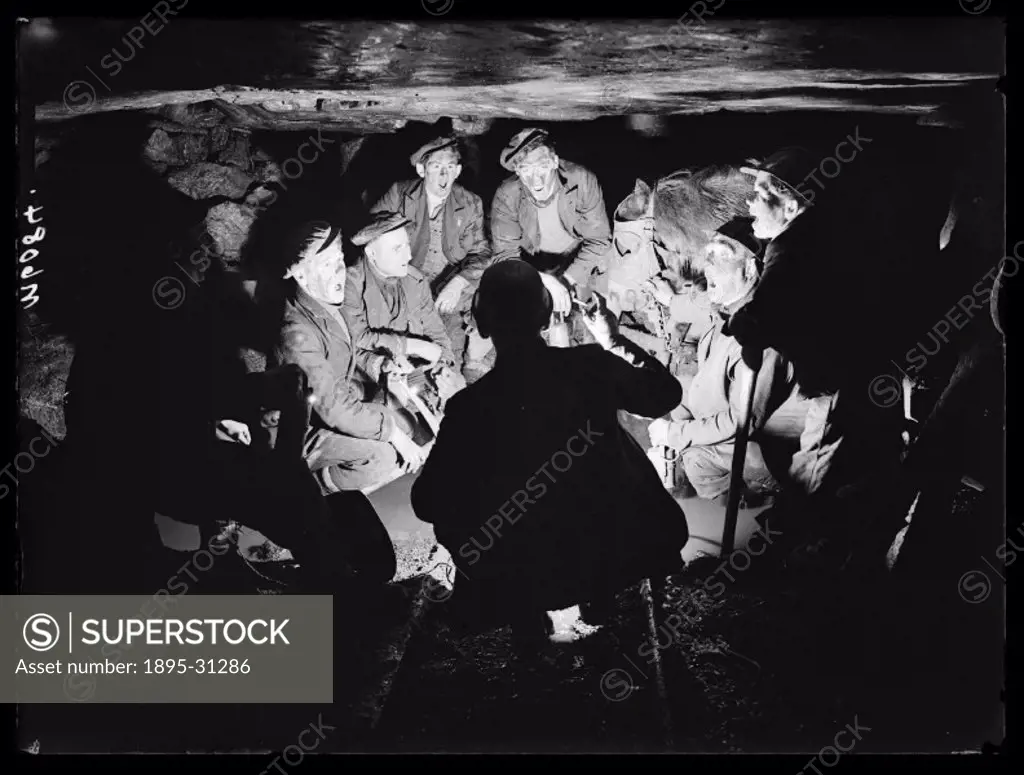 A photograph of a group of miners singing Christmas carols underground at the Bryn Varteg Colliery, Ystradgynlais, Wales, taken by Esten for the Daily...