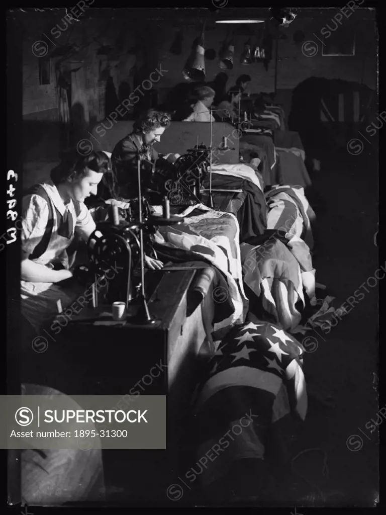 A photograph of women sewing flags, taken by Greaves for the Daily Herald newspaper on 3 April, 1945.   These women are at work in a South London fact...