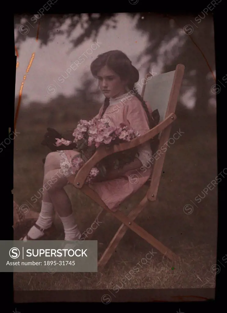 An autochrome of her daughter sitting in a garden chair holding a large bunch of freshly picked flowers, taken by Etheldreda Janet Laing. In the summe...