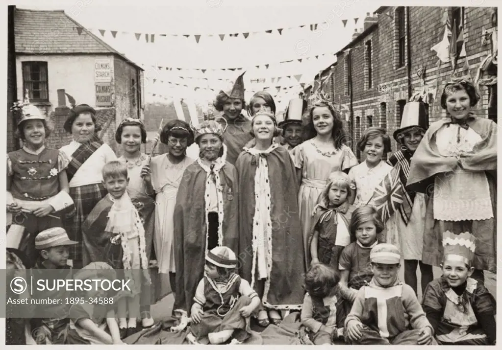 A photograph of children wearing fancy dress in Flint Street, Cardiff, Wales,taken by an unknown photographer in May 1937. The children are taking par...