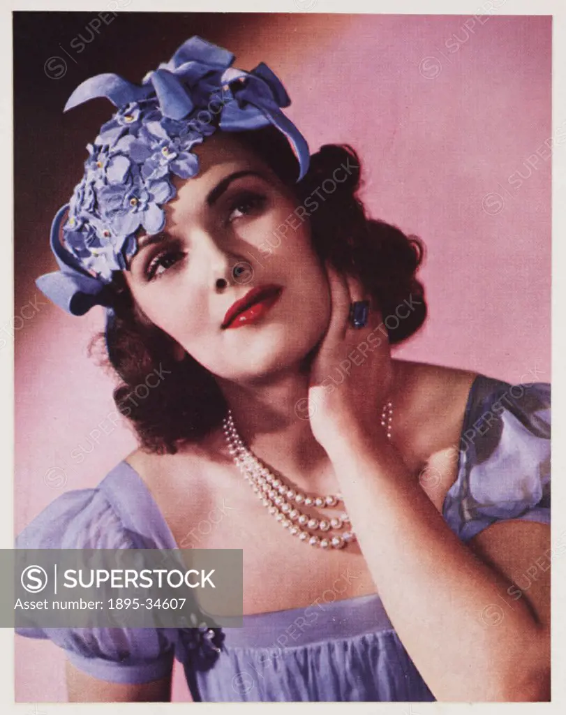 A Kodachrome colour photograph of a woman modelling a decorative hat.