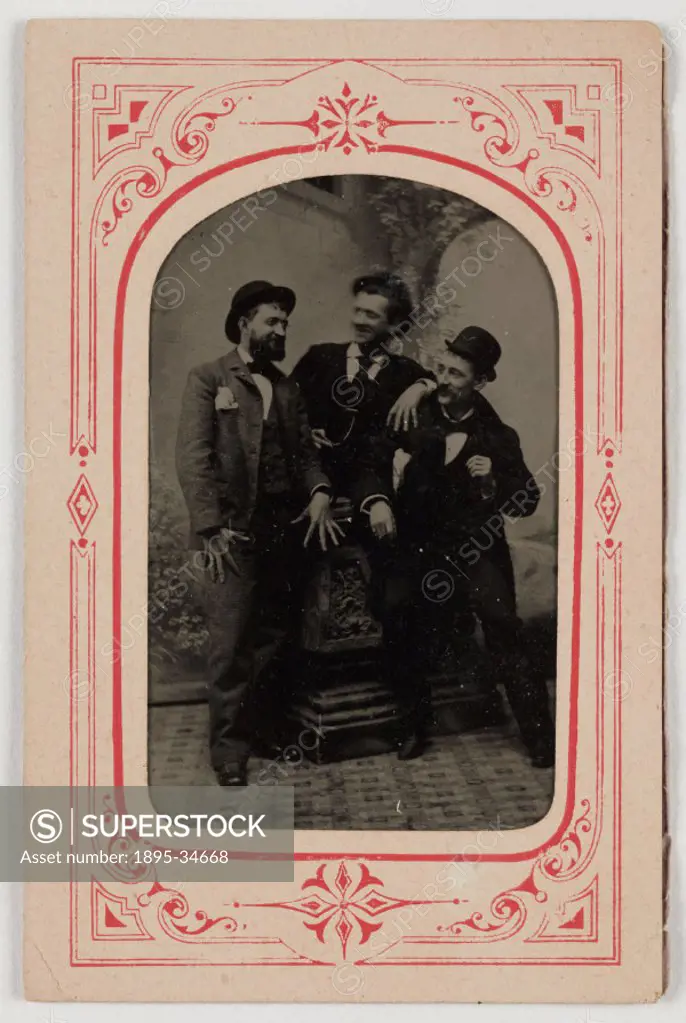 A tintype photograph of three smartly-dressed men in a relaxed and jovial pose in a photographer´s studio,  taken by an unknown photographer in about ...