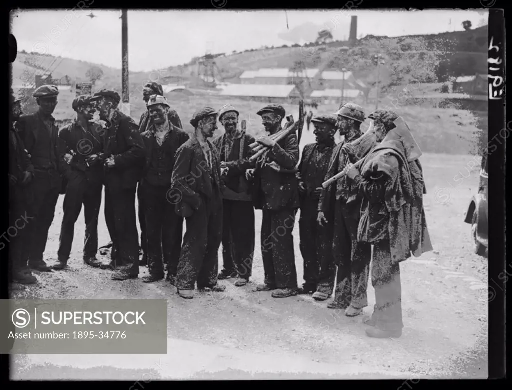 A photograph of miners gathering in the street to chat before returning to their homes in Bedwas, Wales following successful strike action, taken by E...