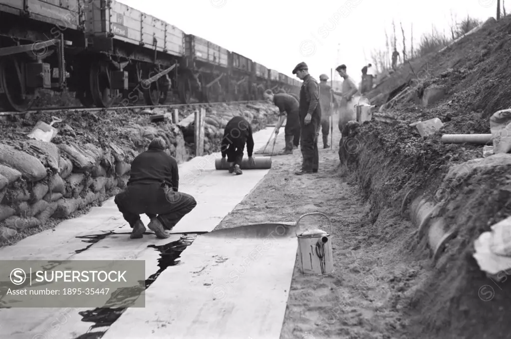 Workers building track at Pitsea, Essex, 2 March 1958. The workers are putting the soil and ballast in place before laying the track.  Track was easie...