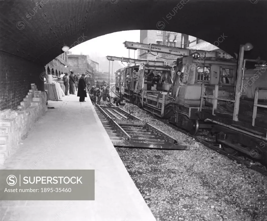 Workers putting track in place at Stoke Newington, London, 20 April 1958. Many miles of track were electrified in the 1950s and 1960s, and the track o...