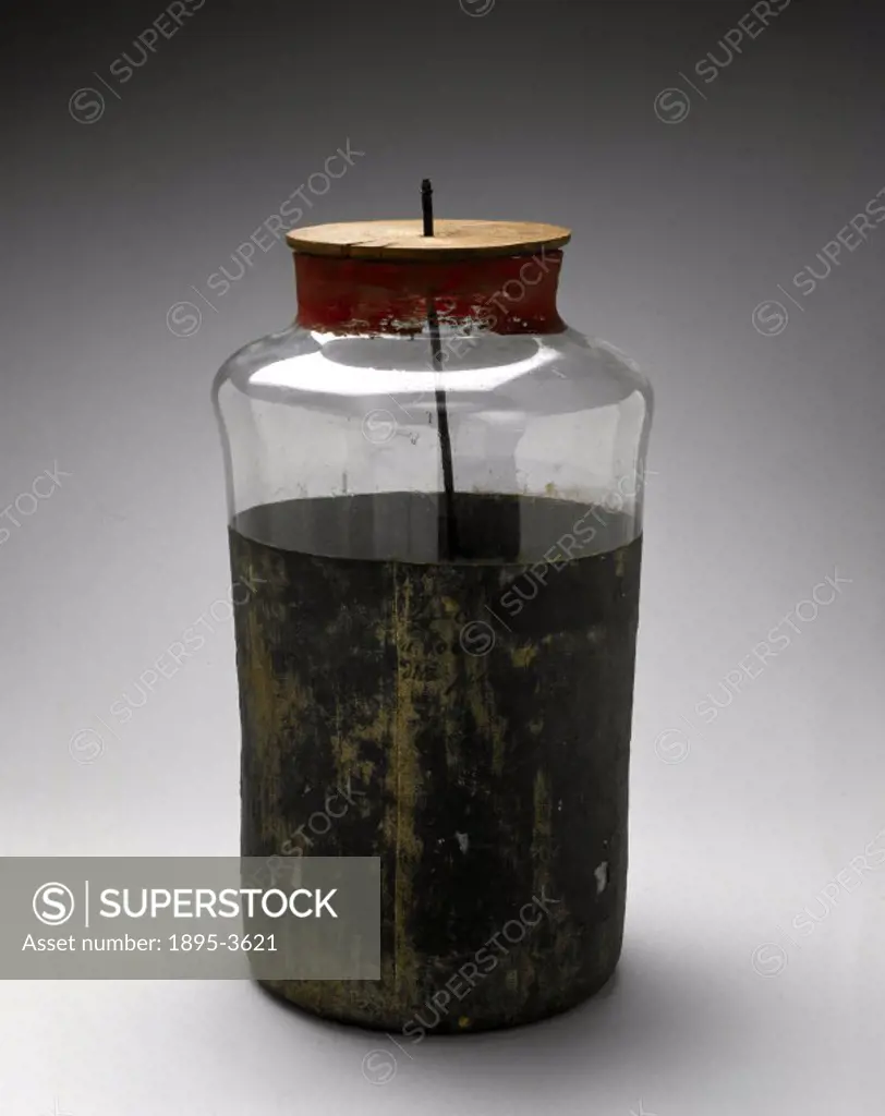 Large Leyden jar with wooden cap fitted with metal hook and short length of chain. This was a device for storing an electrical charge, or capacitor, w...