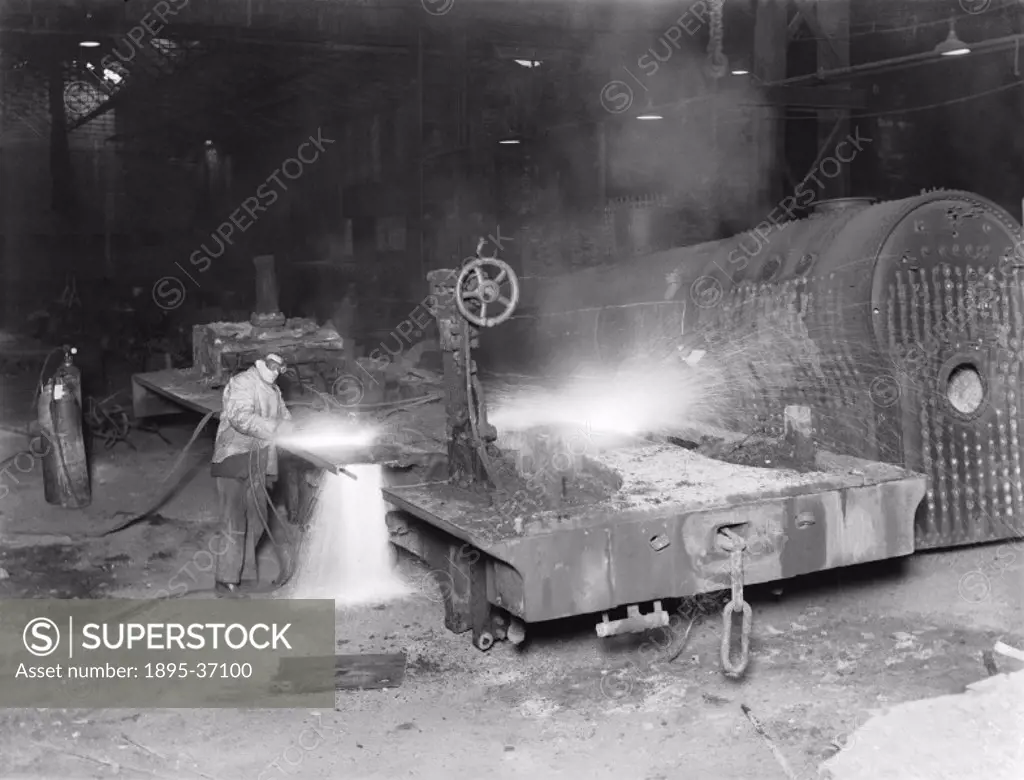 Welder working on a steam locomotive´s frames at Derby works, about 1950. The welder is wearing safety goggles and heavy clothing that gives some prot...