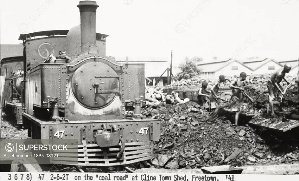 2-6-2 tank engine number 47 at a motive power depot, Freetown, Sierra Leone, 1941.   Workers are shovelling coal from wagons, to fuel the locomotive. ...