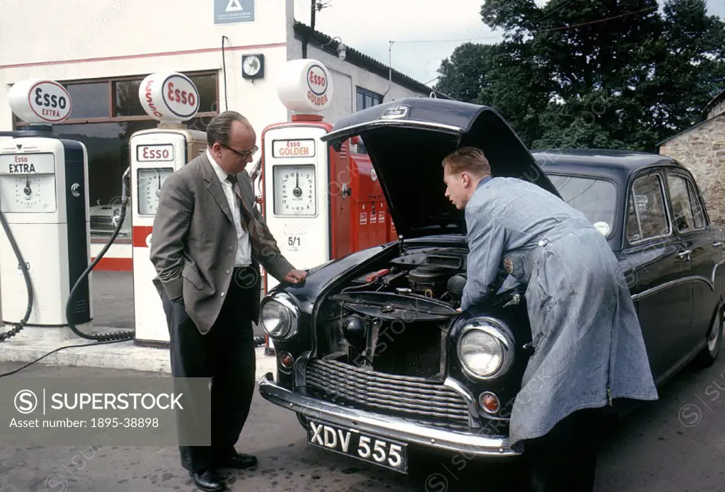 Worker checking a car engine at an Esso Petrol station, 1963.  At this time road traffic in Britain was building up. By the 1960s it was common for pe...