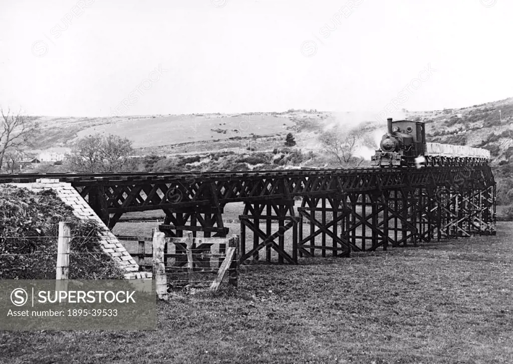 Freight train, hauled by a steam locomotive on a viaduct on the Torrington & Marland Railway, about 1925. The train is carrying empty clay wagons.  Th...