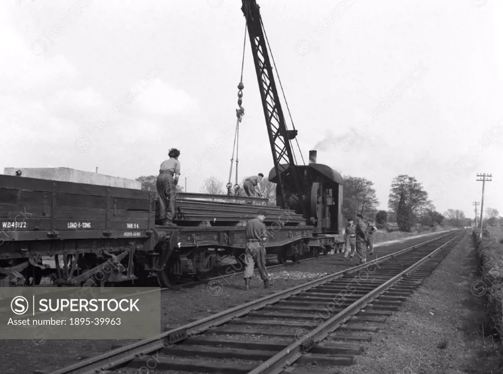 Steel girders being loaded onto a railway wagon, with the aid of a steam powered crane, by Selwyn Pearce-Higgins, 1961.  Cranes are an invaluable mach...