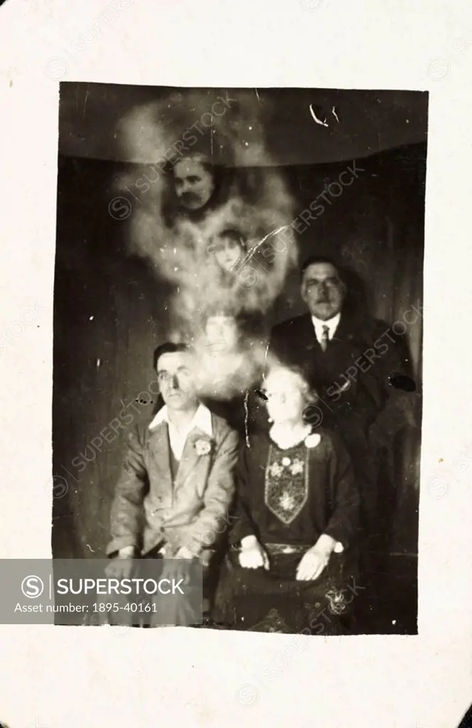 A photograph of a family group, possibly taken by William Hope (1863-1933). Two faces - that of a man and a girl - appear, surrounded in ´mist´, above...