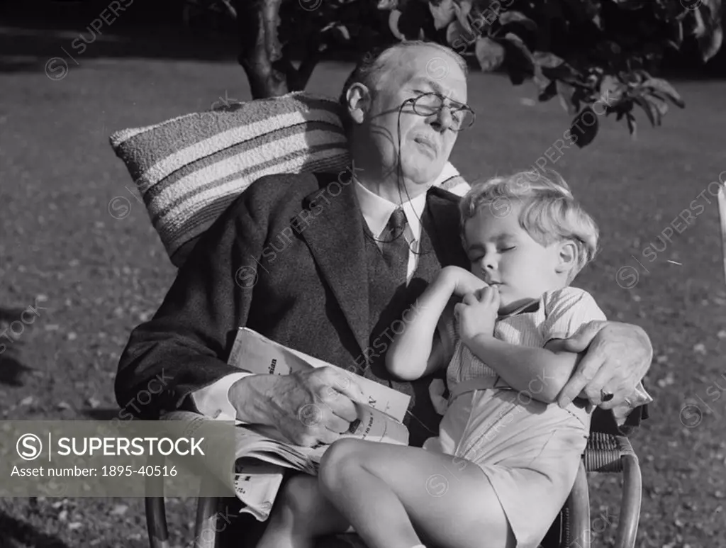 A boy and his grandfather in a chair in the garden, c 1930s