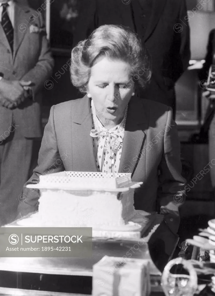The Prime Minister blows out birthday cake candles.