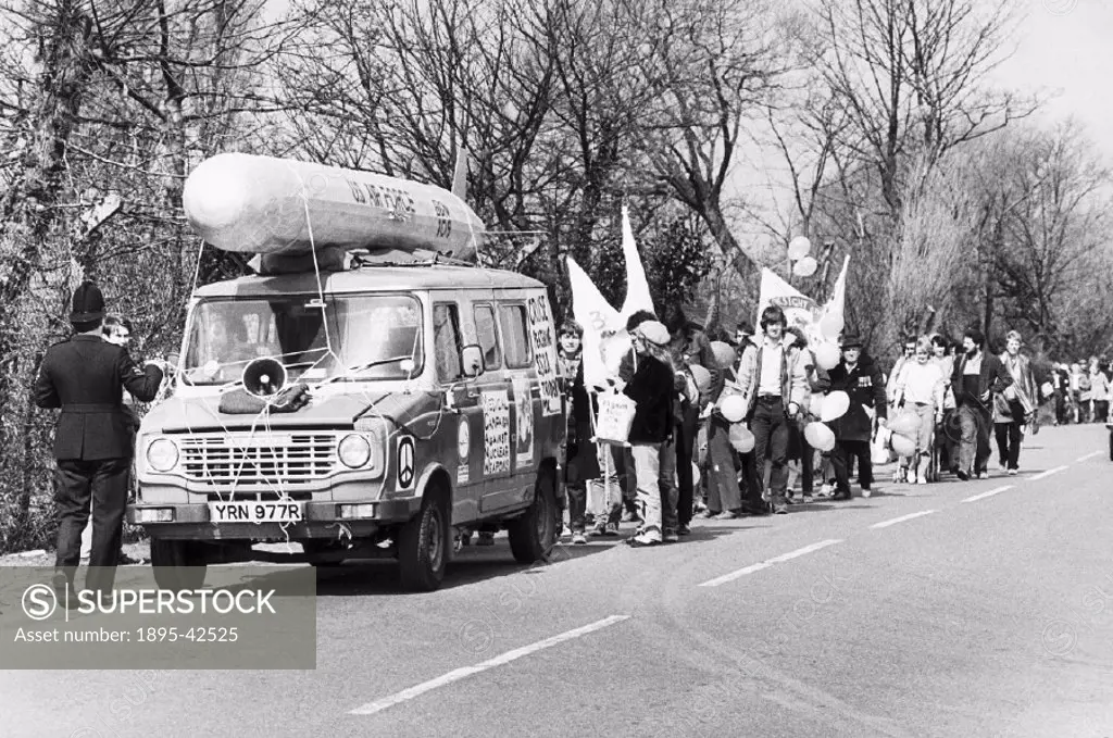 Some of the first of thousands arrive at the entrance to the US base at Burtonwood. A van carrying a mock missile leads the procession. Posters on the...
