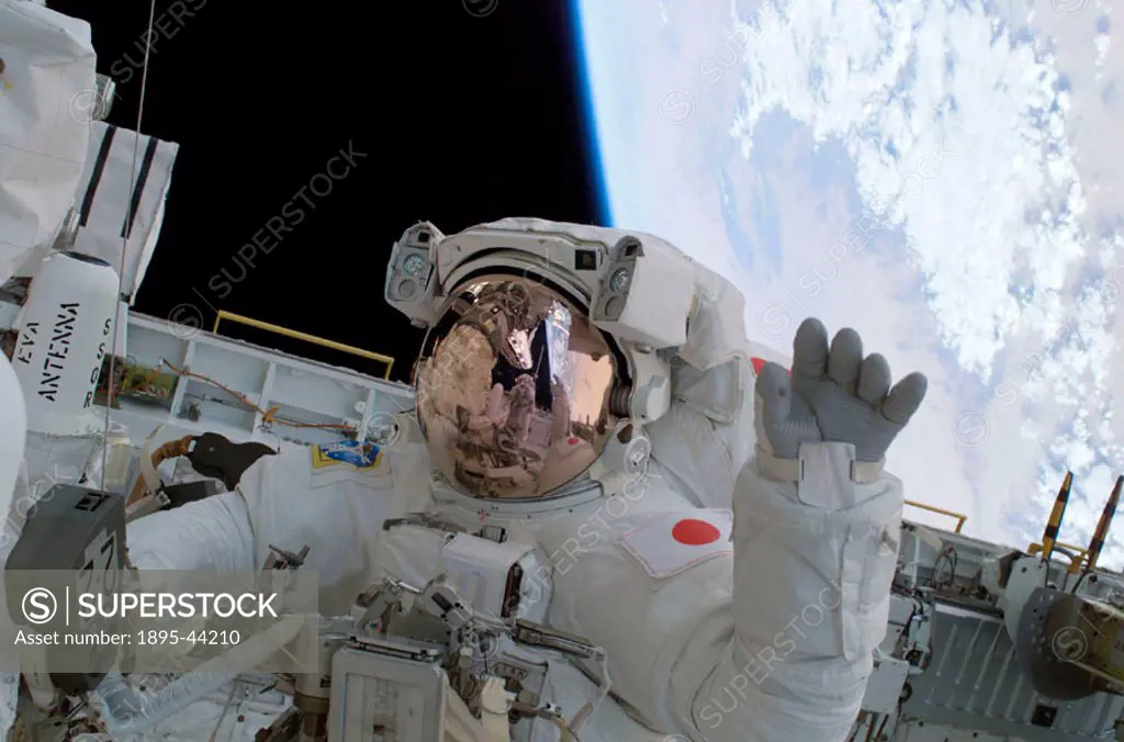 STS-114 astronaut Soichi Noguchi waves from the payload bay of the Space Shuttle Discovery, backdropped by the Earth below. During the mission´s secon...