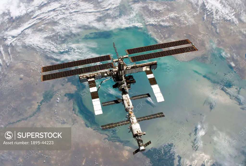 Backdropped by a colourful Earth, this full view of the International Space Station was photographed from the Space Shuttle Discovery during the STS-1...