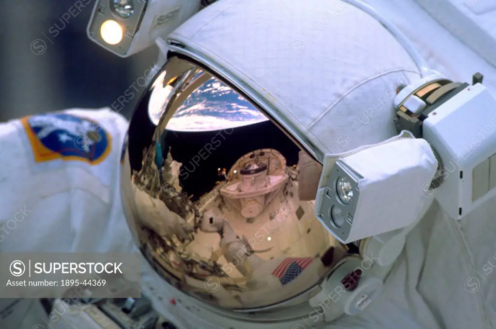 The Earth´s horizon and the Shuttle Discovery are reflected in a spacewalking astronaut´s visor during the STS-103 mission in December 1999.