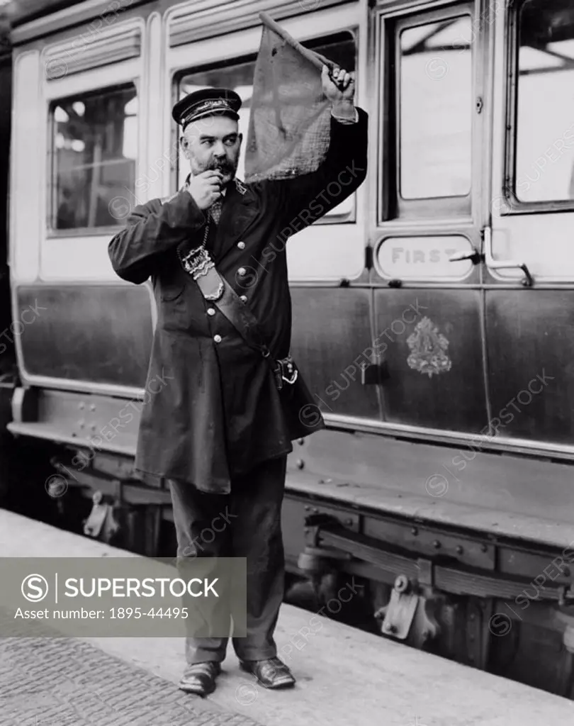 A guard from the LNWR gives the right  away’ signal with a flag at Holyhead station.