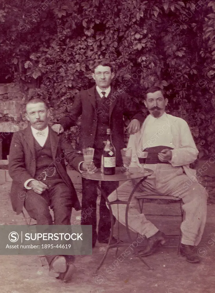 Photograph showing three gentleman sharing a bottle of Absinthe Pernod Fils. Two of the glasses show the traditional band or ´cordon´ at the base, des...
