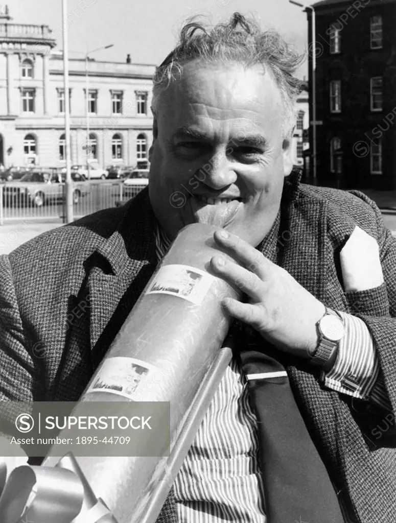 Rochdale MP Cyril Smith gets to grips with a giant stick of rock that was presented to him outside Rochdale Town Hall for charity.’