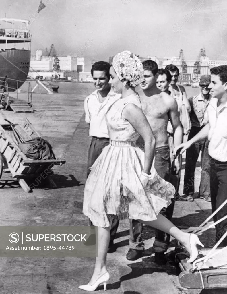 Italian dockworkers stop to admire Liz Taylor arriving from Capri for a holiday before beginning work on ´Cleopatra´.
